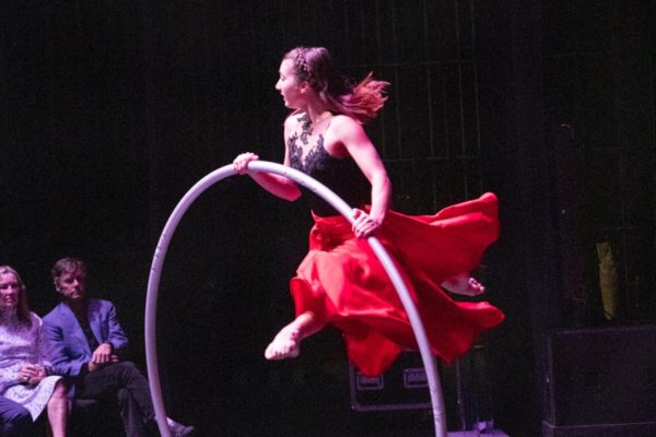 jumping in a cyr wheel wearing a red skirt