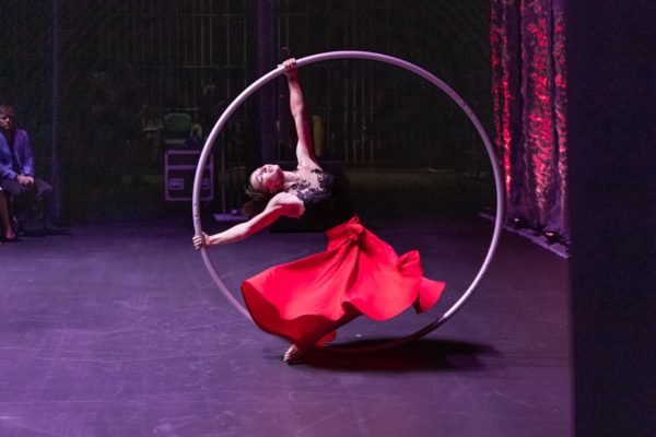 arching back spinning in a cyr wheel wearing a red skirt