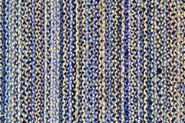closeup of a hand braided rug with blue and yellow fabrics