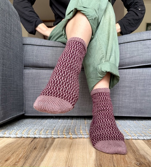 Front view of the Stripe Tease Socks, a colourwork sock knitting pattern featuring broken stripes