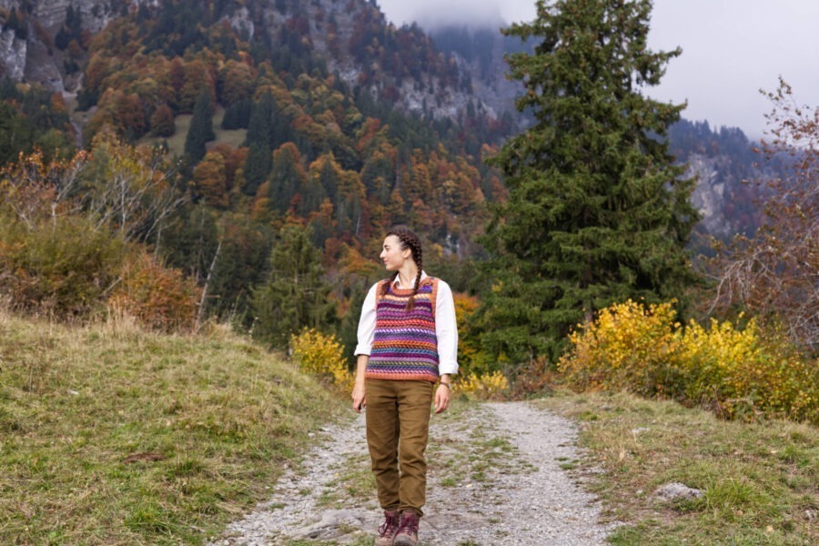 standing on a mountain road wearing steek exposure therapy, a colourwork knitted vest