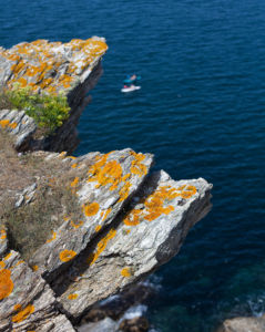 Jagged cliffs by the ocean with kayaks in the background