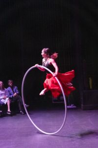 jumping in a cyr wheel wearing a red skirt